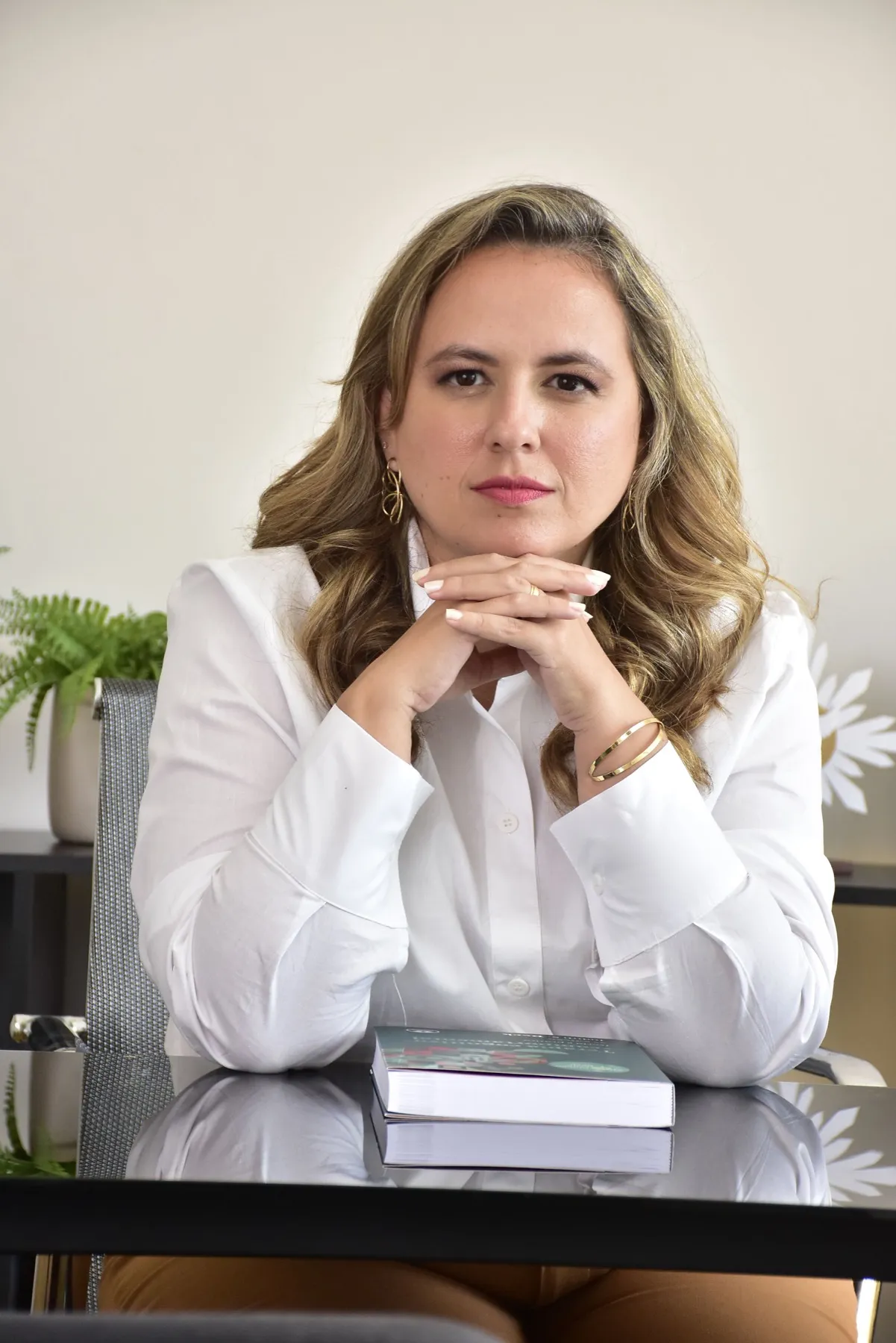 Psicóloga Maruscka Souza sorrindo levemente, sentada à mesa do consultório